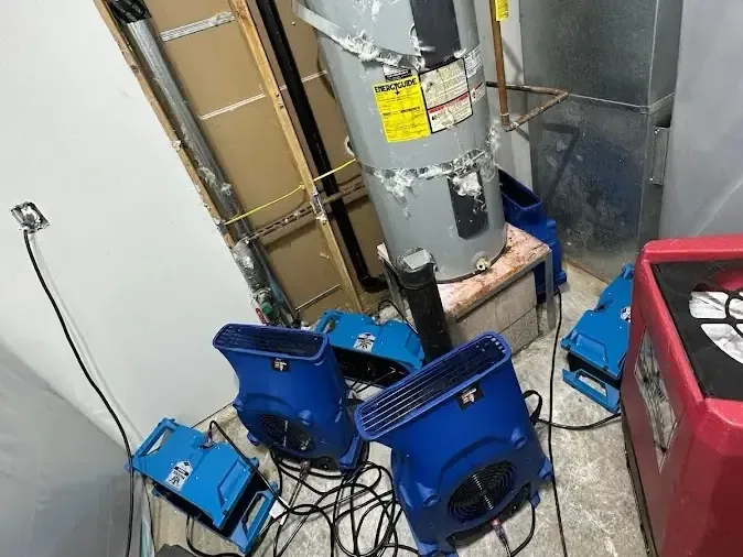 Air movers and a dehumidifier drying out a water heater closet