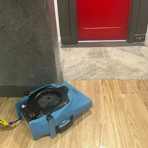 Air movers drying a living room floor near a sliding glass door after storm runoff