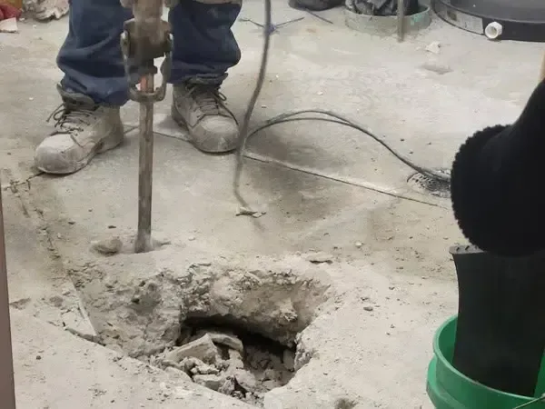 Concrete slab broken open with a breaker to reach a leaking pipe under a home