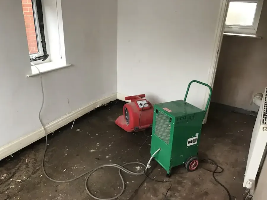 Air mover and dehumidifier drying a room after the flooring was removed